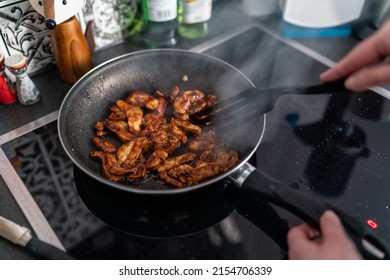 Woman Uses A Spatula To Prepare Chicken Teriyaki In A Pan On The Stovetop In The Kitchen. Healthy And Delicious Food At Home.