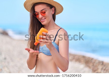 Woman uses sunscreen cream during sunbathing on the sea. Sun protection and skin care in hot summer weather 
