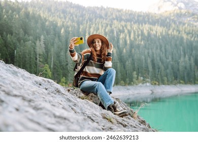 Woman uses a telephone for take pictures, make selfies and video calls friends and family on mountains background. Travel and wanderlust concept. - Powered by Shutterstock