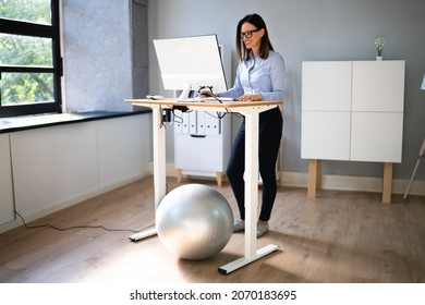Woman Using Adjustable Height Standing Desk In Office For Good Posture