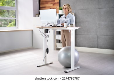 Woman Using Adjustable Height Standing Desk In Office For Good Posture