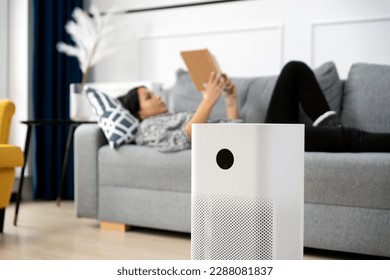 Woman using air purifier, fresh air at home