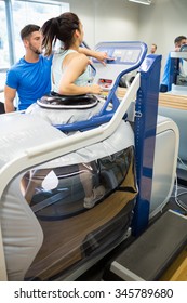 Woman Using An Anti Gravity Treadmill Beside Trainer At The Gym