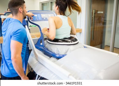 Woman Using An Anti Gravity Treadmill Beside Trainer At The Gym