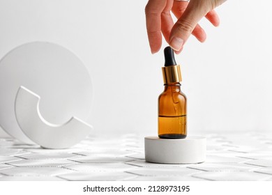 Woman using aromatic lotion, oil, Hyaluronic acid or collagen in brown bottle with pipette. Mock up