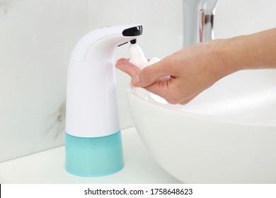 Woman Using Automatic Soap Dispenser In Bathroom, Closeup