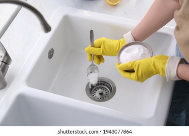 Woman using baking soda to unclog sink drain, closeup