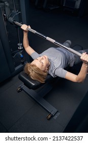 Woman Using Barbell Press Bench Machine During Workout