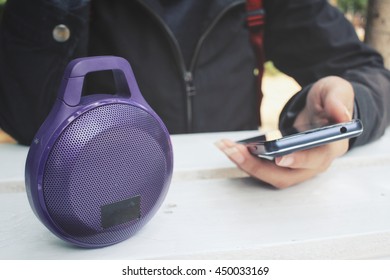 Woman Using Bluetooth Speaker With Smart Phone