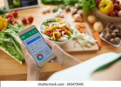 Woman using calorie counter application on her smartphone - Shutterstock ID 343475045