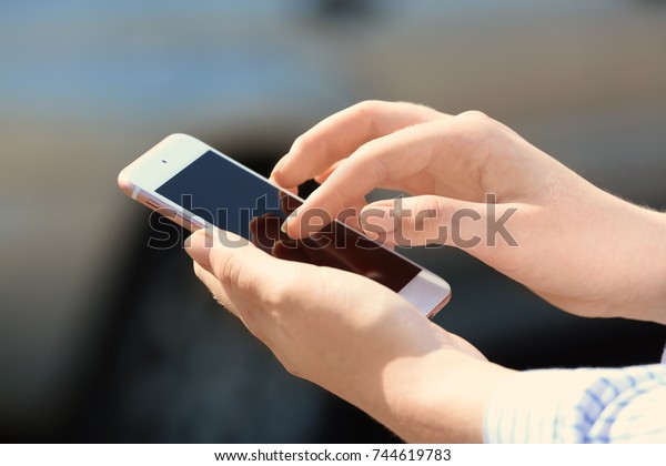 Woman\
using cell phone to call taxi on street,\
closeup