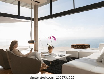 Woman using cell phone in modern living room - Shutterstock ID 2303731755