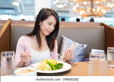 Woman using cellphone and having lunch - Powered by Shutterstock