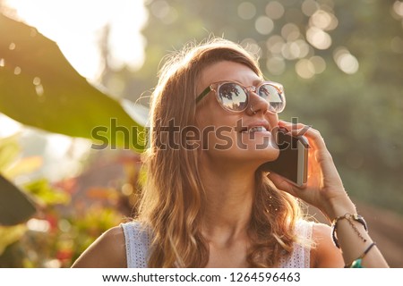 Woman using cellphone outdoors in the park / garden.