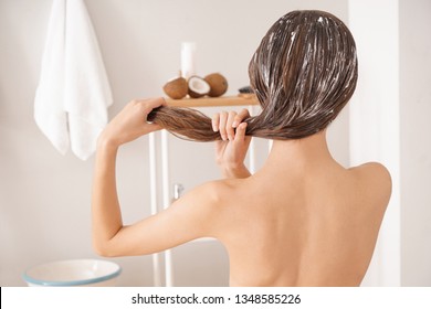 Woman Using Coconut Oil For Hair In Bathroom