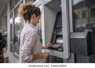 woman using credit card and withdrawing cash at the ATM
