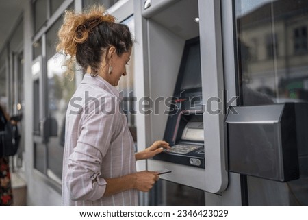 woman using credit card and withdrawing cash at the ATM