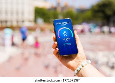 Woman using daily activity tracking app on phone showing 10 000 steps daily goal achievement - Shutterstock ID 1971691394