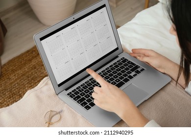 Woman Using Digital Calendar On Laptop In Bedroom