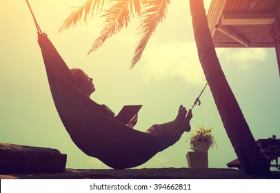 Woman an using a digital tablet computer while relaxing in a hammock - Powered by Shutterstock