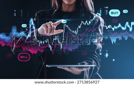 Woman using digital tablet interacting with forex and crypto chart hologram, futuristic concept on dark background with buy and sell indicators visible