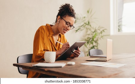 Woman using digital tablet while sitting at home. Female designer sketching on a graphic tablet while working at home.