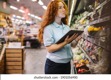 Woman Using A Digital Tablet While Doing Inventory Check In A Grocery Store. Female Trainee Employee Working In Supermarket.