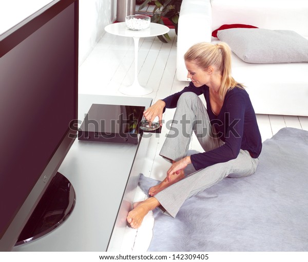 woman using dvd player in\
her flat