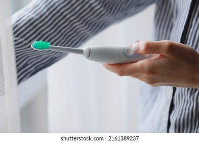 Woman Using Electric Toothbrush At Home. Technology And Health Care.