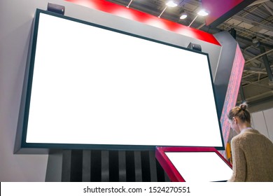 Woman Using Electronic Kiosk And Looking At White Blank Large Interactive Wall Display At Modern Technology Exhibition, Museum. Mock Up, Isolated, White Screen, Copyspace, Template, Education Concept