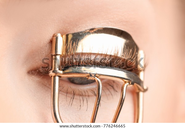 Woman using eyelash curler,\
closeup
