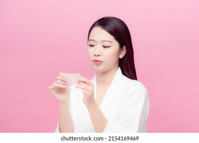 Woman using facial oil blotting paper.