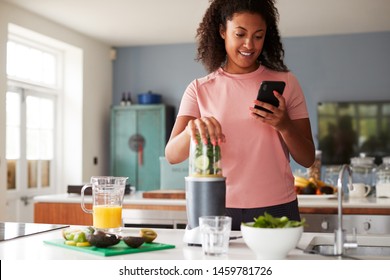 Woman Using Fitness Tracker To Count Calories For Post Workout Juice Drink He Is Making