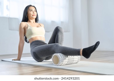 A woman using a foam roller to relax the back of her knees - Powered by Shutterstock