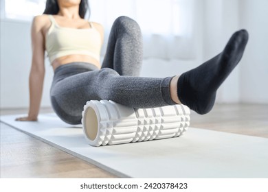 A woman using a foam roller to relax the back of her knees - Powered by Shutterstock