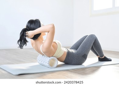 Woman using a foam roller to release myofascial muscles in her back - Powered by Shutterstock