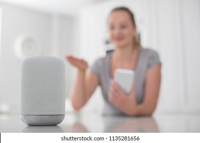 Woman Using Gesture Control With Digital Assistant At Home In Kitchen