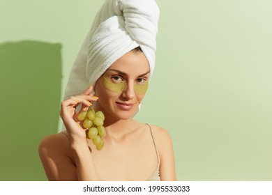 Woman Using Grapeseed-based Eye Patches On Pastel Green Background. Natural Sustainable Skincare. Beauty Treatment Concept.