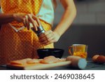 
Woman Using ground pepper to season the meat. Cook seasoning her meal with a mix of black and red pepper 
