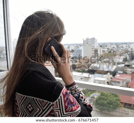 Woman using her cellphone at a balcony with a city view