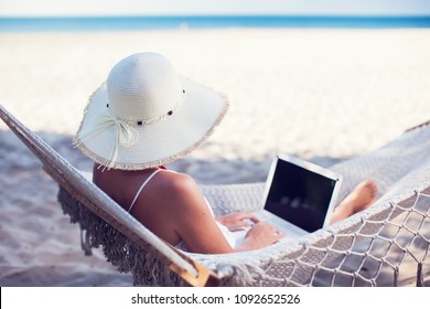 Woman Using Her Laptop In Hammock On The Beach