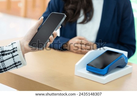 A woman using her mobile to made a payment wireless with EDC machine or credit card terminal. Mobile payment concept with virtual credit card. Shopping, retail and modern digital bank concept.