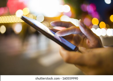 Frauen, die ihr Mobiltelefon auf der Straße benutzen, Nachtlicht-Hintergrund