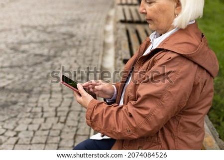 Woman using her mobile phone, reading messages on mobile phone in a city park