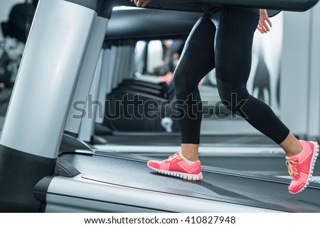Woman using incline threadmill in modern gym. Incline threadmills are used to simulate uphill walking or running and deliver additional workout benefits to users.