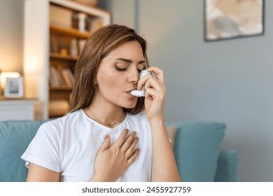 Woman using inhaler while suffering from asthma at home. Young woman using asthma inhaler. Close-up of a young woman using asthma inhaler at home. - Powered by Shutterstock