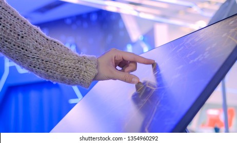 Woman Using Interactive Touchscreen Display With Unrecognizable Virtual Map At Modern Technology Show With Futuristic Interior