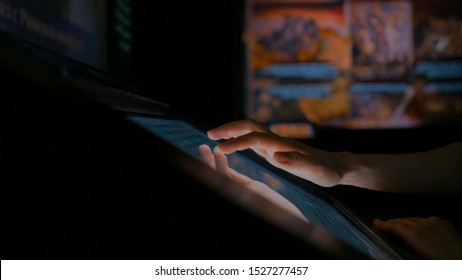 Woman using interactive touchscreen display in modern historical museum. Evening time, lowlight. Education and entertainment concept. Close up shot