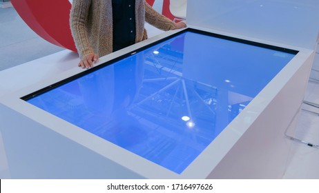 Woman Using Interactive Touchscreen Display Table At Urban Exhibition - Scrolling And Touching