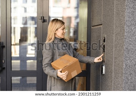 woman using intercom at building entrance.